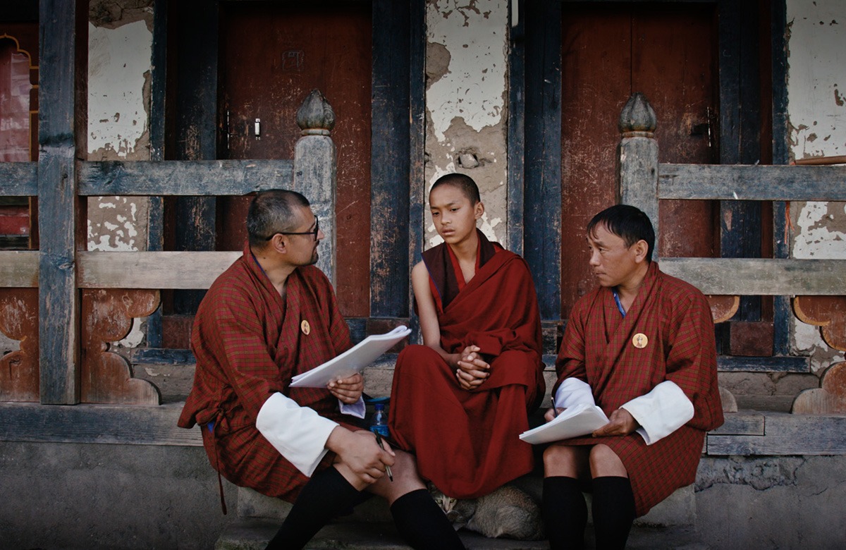 Three monks sitting outside a building.