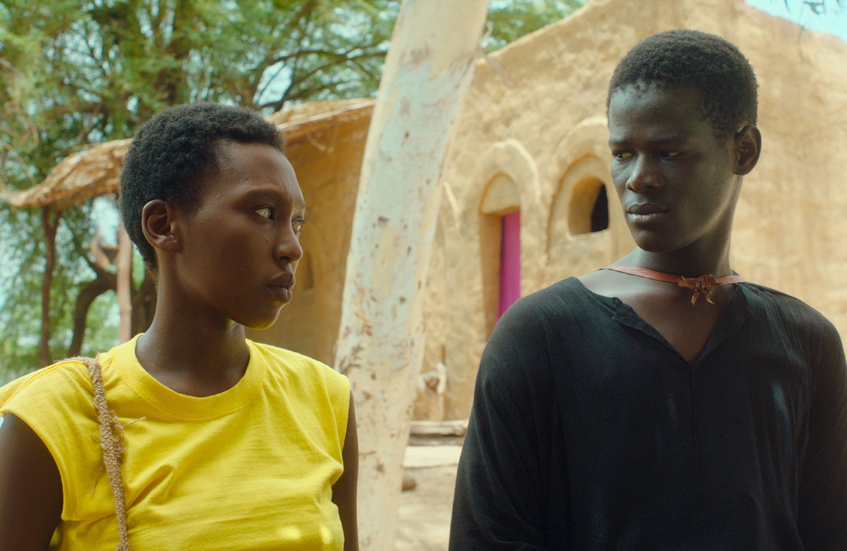 A man and a woman stand looking at each other.