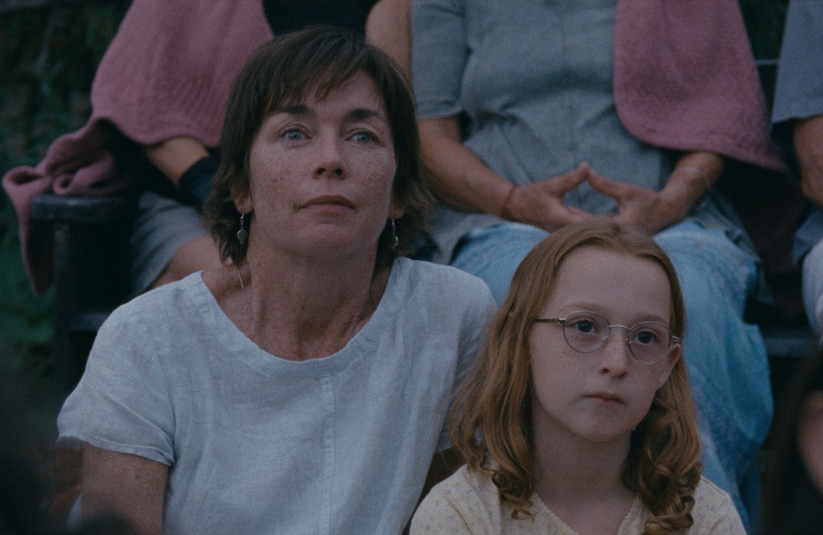 A woman and a girl sitting on a bench.