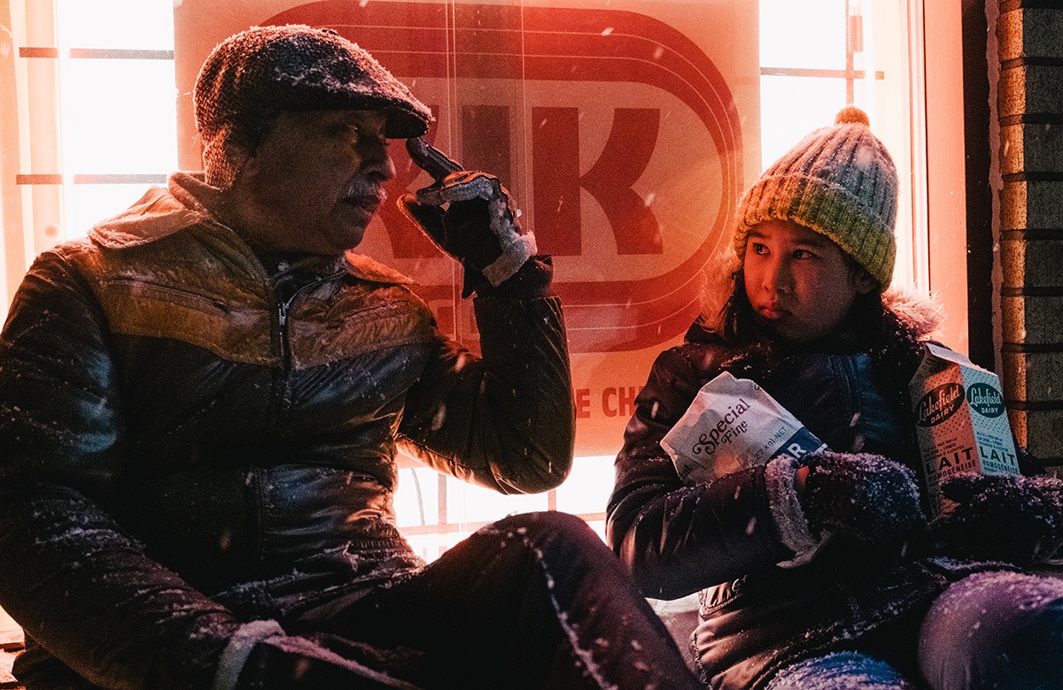 A man and a girl outside a store in the snow.