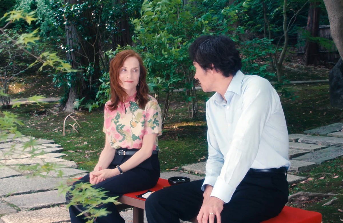 A woman and man sitting outside on a bench.