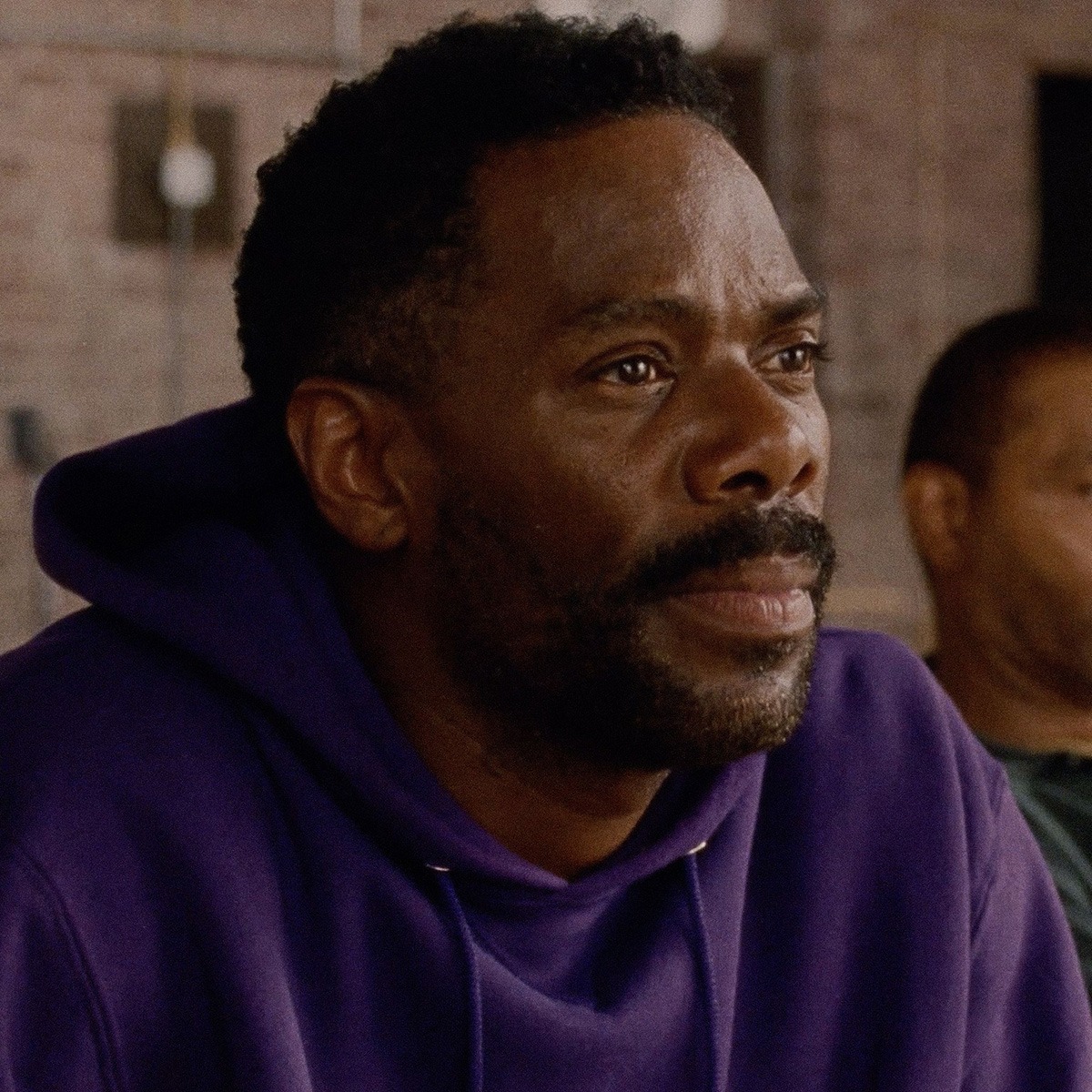 A man sitting in a purple hoodie.